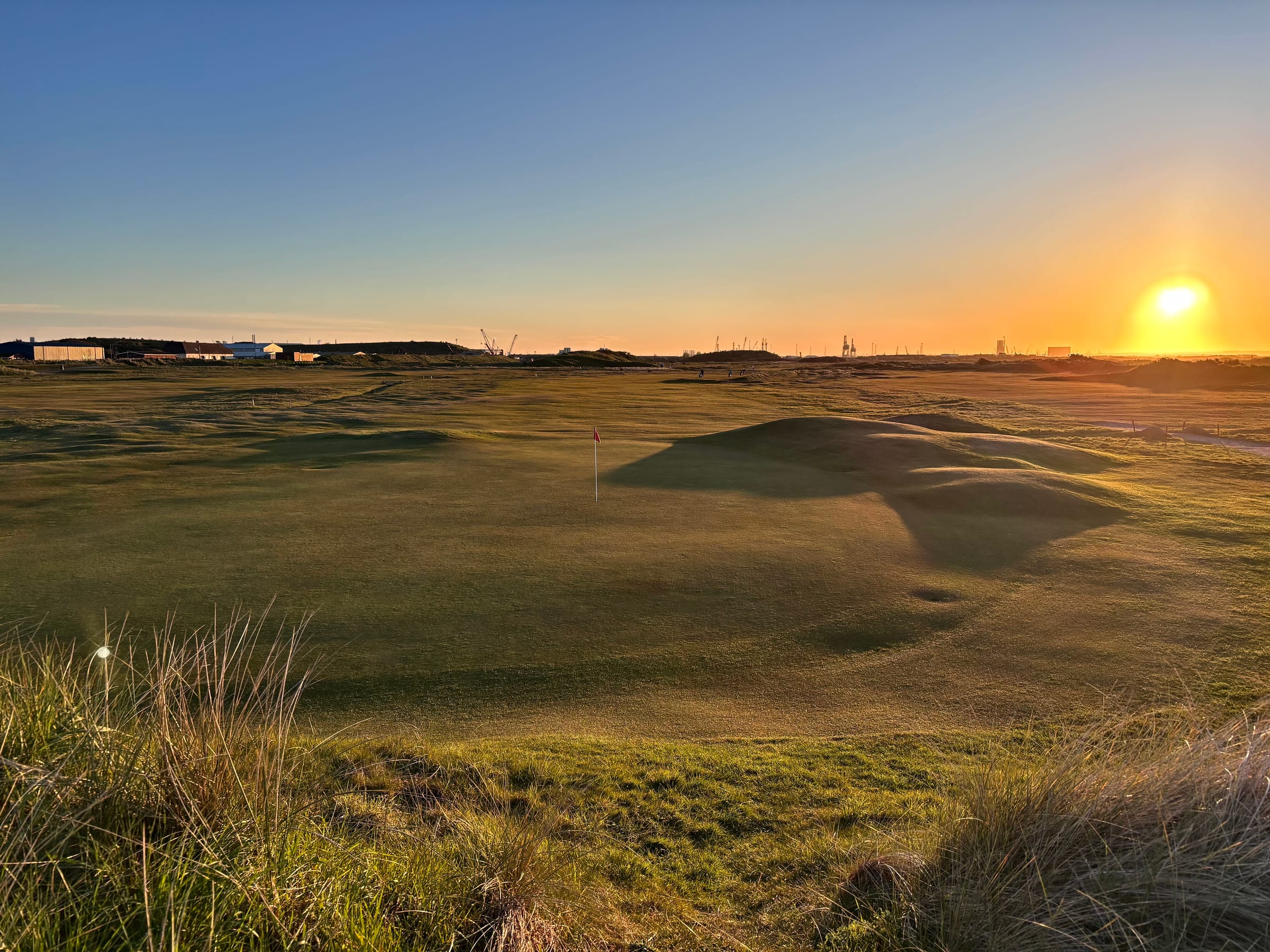 A green on Cleveland Golf Club's links, framed by dunes at golden hour